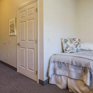 A simple bedroom with a single bed, pillows, and a closed door.