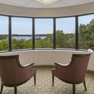 Two chairs facing a scenic lake view through large windows.