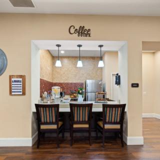 A cozy kitchen nook with a coffee bar, featuring three chairs and pendant lighting above the counter.