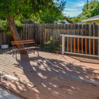 A tranquil backyard deck with a wooden bench and surrounding trees.