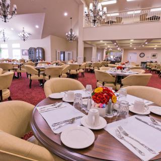 A spacious dining room with elegantly set tables and comfortable seating.