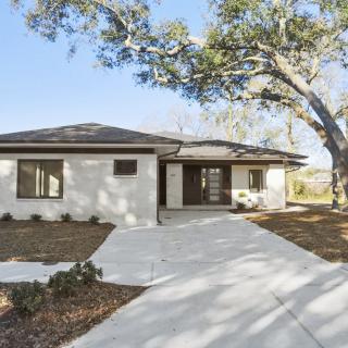 A single-story house with a driveway and surrounding trees.