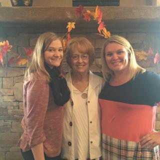 Three people posing together indoors with autumn-themed decor.