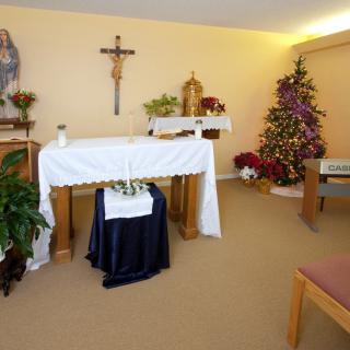 A small chapel with an altar, crucifix, and Christmas decorations.