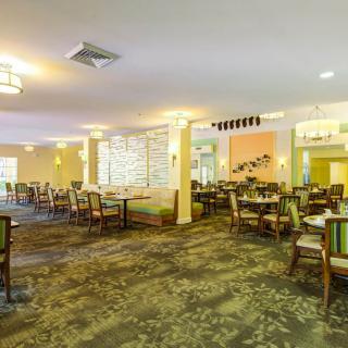 A spacious and well-decorated dining area with multiple tables and chairs, featuring soft lighting.
