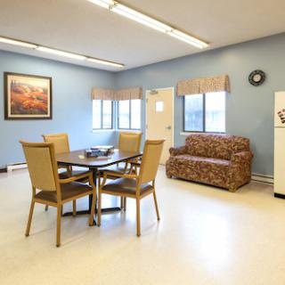 A cozy dining area featuring a table and chairs, a colorful sofa, and large windows that let in natural light.