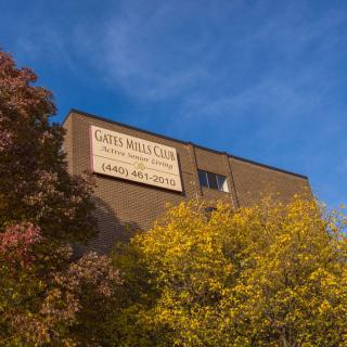 A building with a sign, surrounded by autumn trees under a clear blue sky.