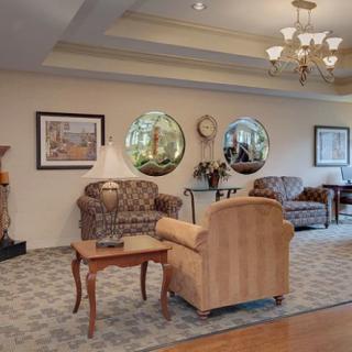 A cozy living room with elegant furniture, decorative mirrors, a chandelier, and framed artwork.
