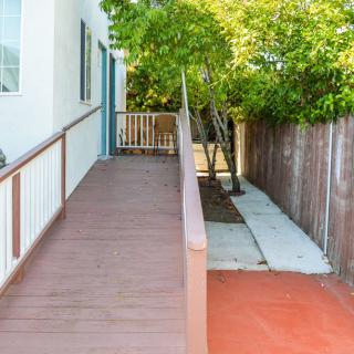 An accessible ramp leading to the entrance of a house, surrounded by trees and a wooden fence.