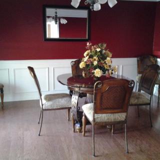 A cozy dining room with a round table, four chairs, and a floral centerpiece.