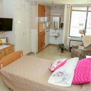 A cozy hospital room with a single bed, television, and comfortable seating.