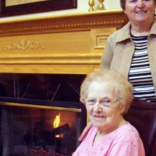 Two women smiling in front of a fireplace.