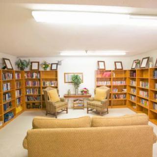 A cozy library space featuring wooden bookshelves filled with books, comfortable seating, and a welcoming atmosphere.