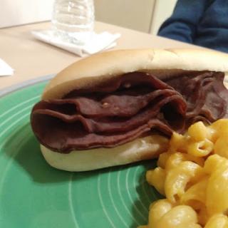 A delicious beef sandwich served with a side of creamy macaroni and cheese.