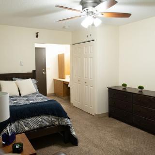 A neatly arranged bedroom with a bed, dresser, and ceiling fan.
