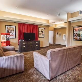 A cozy living room featuring comfortable sofas, a TV, a popcorn machine, and wall posters.