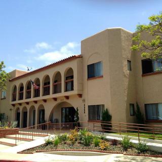 A Mediterranean-style building with arches and landscaped surroundings under a clear blue sky.