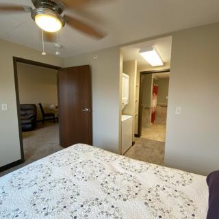 A cozy bedroom with a ceiling fan and visible entrance to an adjoining room.
