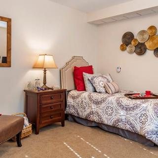 A cozy bedroom with a single bed, decorative pillows, and wall art.