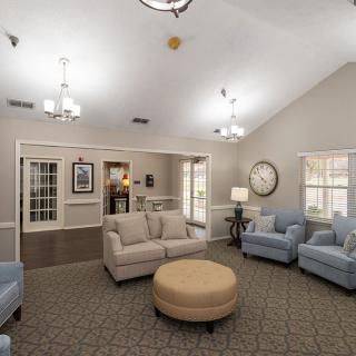 A cozy and well-lit living room with comfortable sofas and chairs arranged around a central ottoman.
