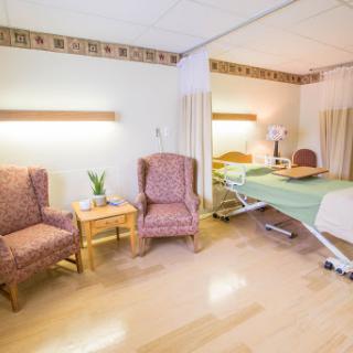 A well-furnished hospital room with comfortable seating and a patient bed.