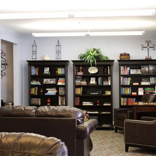 A cozy reading room with bookshelves filled with books and comfortable couches.