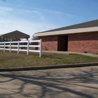 A brick barn with a white fence under a clear blue sky.