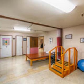 A rehabilitation room equipped with therapy stairs, a wooden table, and exercise ball.