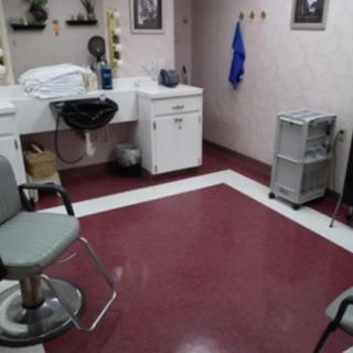 An empty hair salon with chairs, a sink, and a mirror.