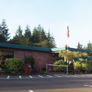 A welcoming building surrounded by lush greenery and an American flag.