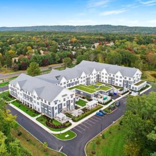 An aerial view of a large residential building surrounded by greenery and parking lots.