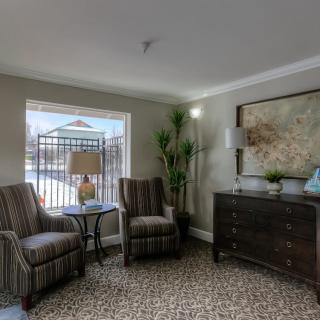 A cozy living room with two striped chairs, a lamp, and a large window letting in natural light.