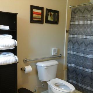 A tidy bathroom with a toilet, shower curtain, and neatly arranged towels on a shelf.