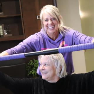 Two women engaging in a joyful exercise session indoors.