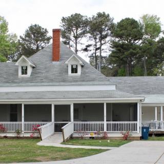 A suburban house with a large porch and a chimney, surrounded by trees.