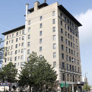 A tall, multi-story building with trees lining the street on a clear day.