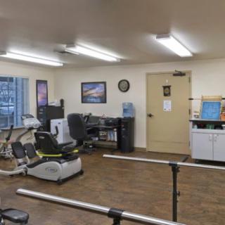 A rehabilitation room equipped with exercise machines and parallel bars for physical therapy.
