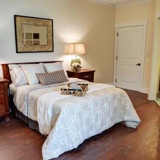 A cozy bedroom with a neatly made bed, nightstands, and soft lighting.