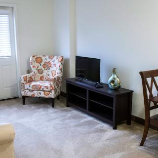 A comfortable living room with a floral armchair and a TV stand.