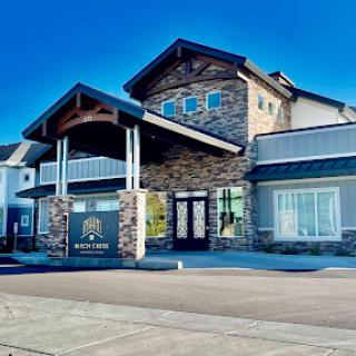 A modern commercial building showcasing a blend of stone and wood architectural elements under a clear blue sky.