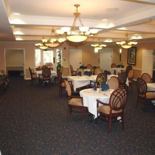 An elegant dining room with neatly arranged tables and chairs, adorned with chandeliers.