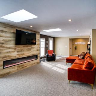 A modern living room with a stylish orange sofa, wall-mounted TV, and a contemporary fireplace.