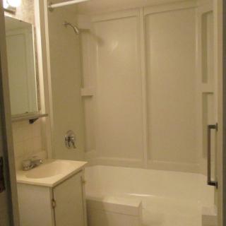 A bathroom with a bathtub and shower, featuring a sink and mirror.