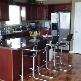 A modern kitchen with dark wooden cabinets and a sleek countertop, featuring bar stools and stainless steel appliances.