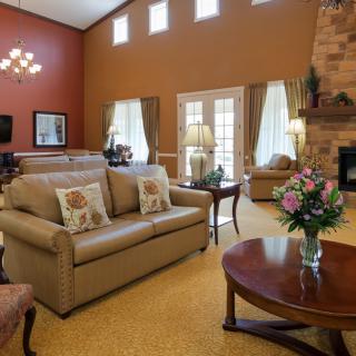 A cozy living room featuring a comfortable sofa, coffee table, and a fireplace, decorated with warm colors and elegant furnishings.