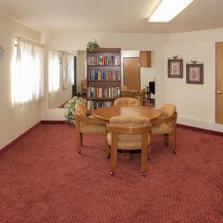 A cozy living room with a table, chairs, and a bookshelf.