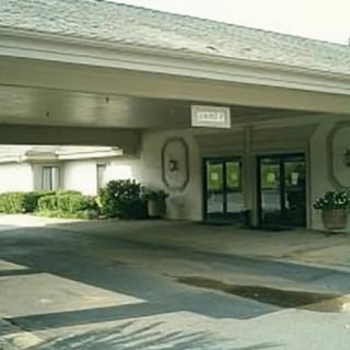 A building entrance with a covered driveway and surrounding landscaping.