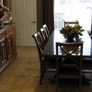 A cozy dining room featuring a wooden table and chairs, complemented by a floral centerpiece.