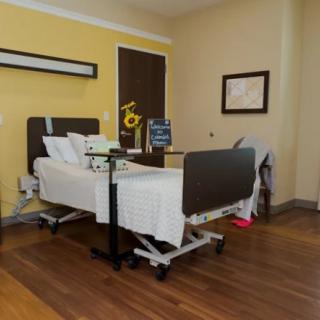 A clean and organized hospital room featuring a bed with medical equipment.