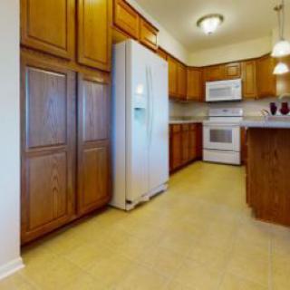 A kitchen with wooden cabinets, modern appliances, and bright lighting.
